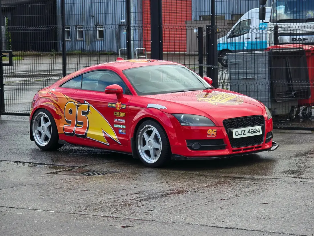 The red race car parked beside a fence